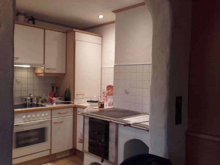 Moderne Elektroinstallation in einer kleinen Küche mit Herd, Fliesen, Geräten und Beleuchtung